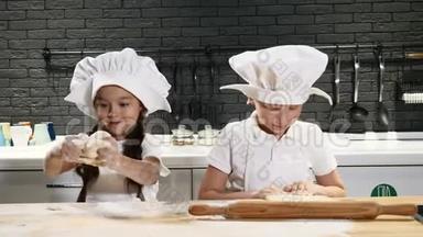 儿童扮演成人职业。 学龄前儿童穿围裙和厨师帽在家厨房<strong>做饭</strong>。 在家<strong>做饭</strong>